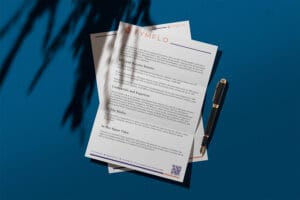 TymFlo branded letterhead with purple accents placed on a blue surface beside a golden pen, featuring the TymFlo logo at top and paragraphs about credentials and services