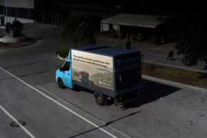 Delivery truck parked on a city street featuring a Breadcrumb advertisement with scenic landscape and travel quote