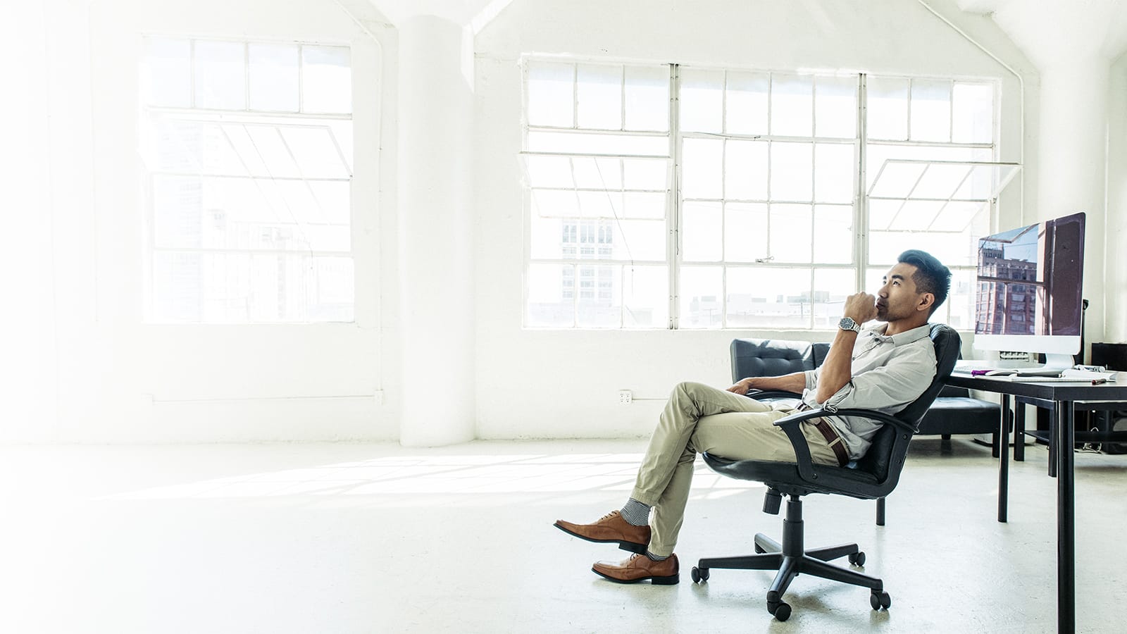 Man sitting in office looking at ceilling thinking